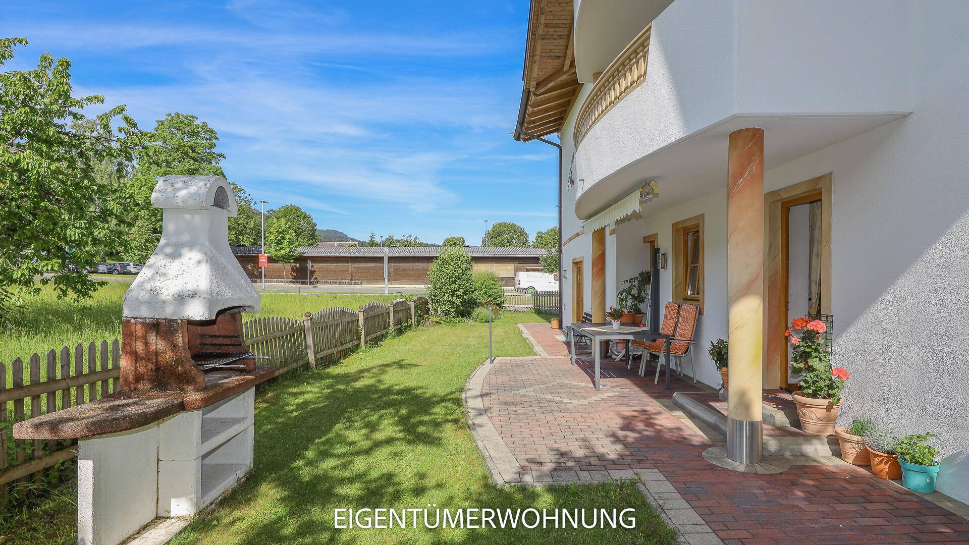 Sonniger Gartenbereich mit Grillplatz und gepflasterter Terrasse für entspannte Stunden.