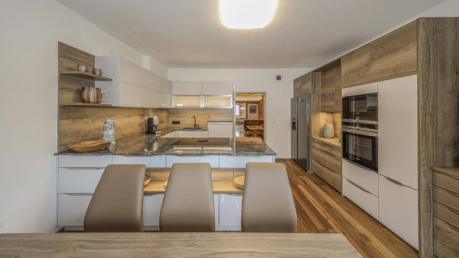 Helle, moderne Küche mit Holzboden, Granitarbeitsplatten und integriertem Essbereich.