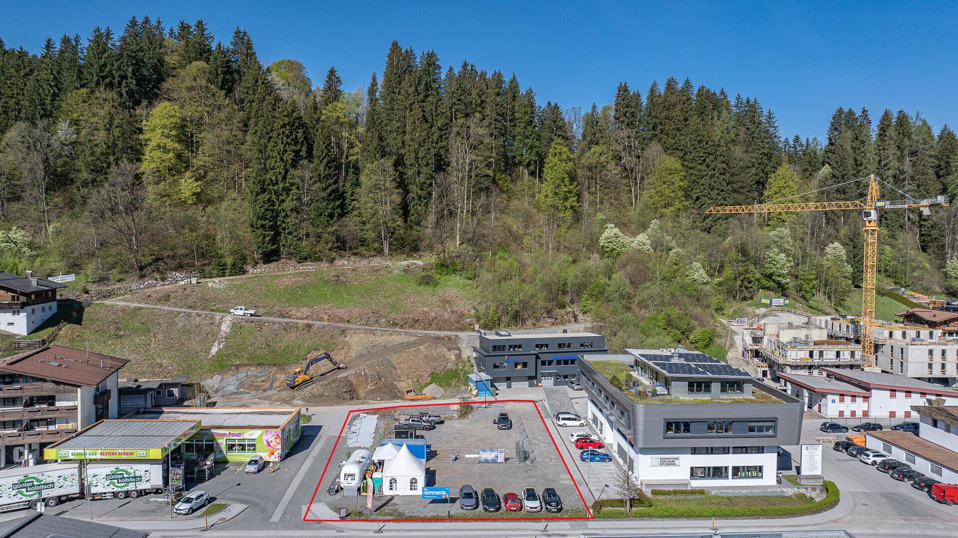 Detailansicht des Grundstücks aus der Luft mit angrenzenden Gebäuden und einer Baustelle am Hang.