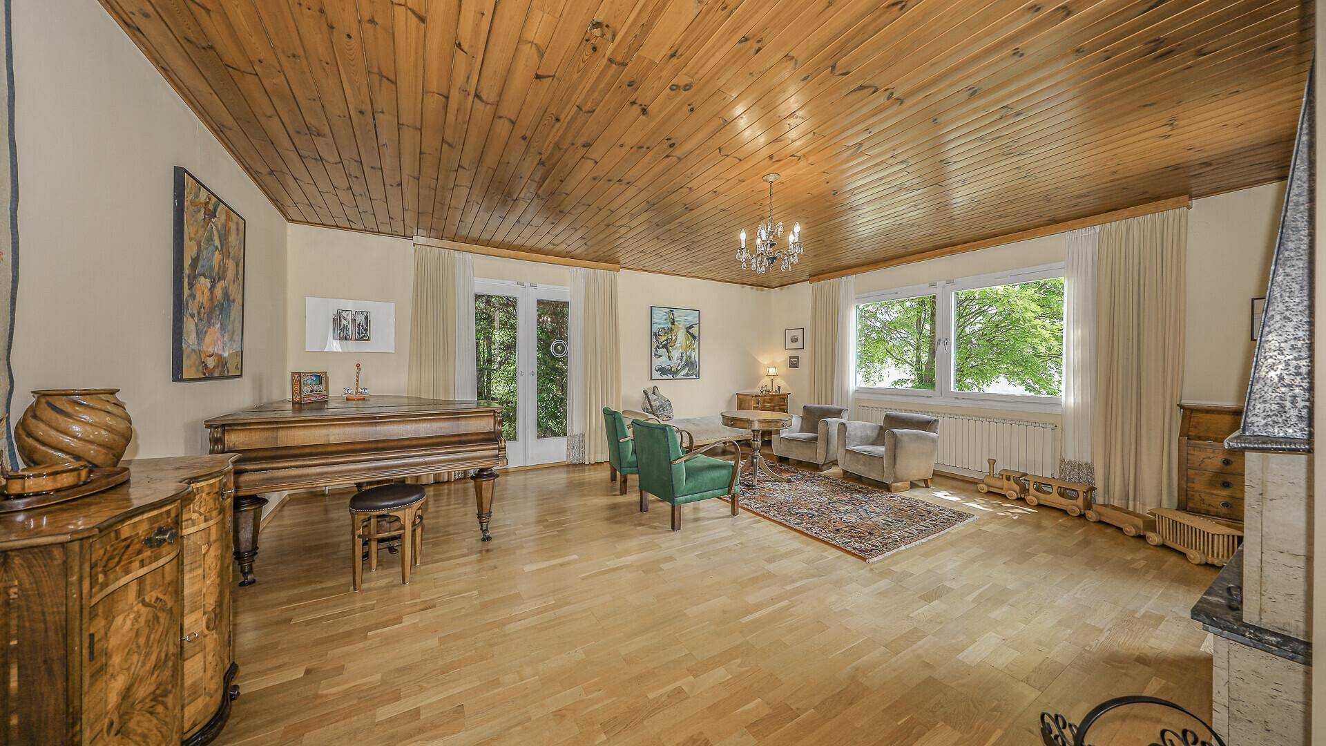Geräumiges Wohnzimmer mit Holzdecke, Parkettboden, klassischem Flügel und Bergblick.