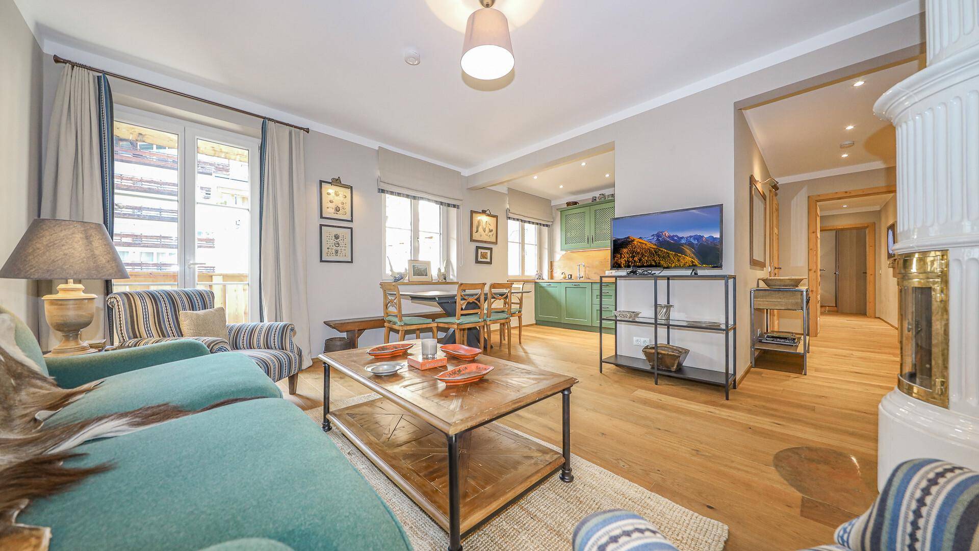 Heller Wohn- und Essbereich mit Holzboden, Kaminofen und Zugang zu einem Balkon.