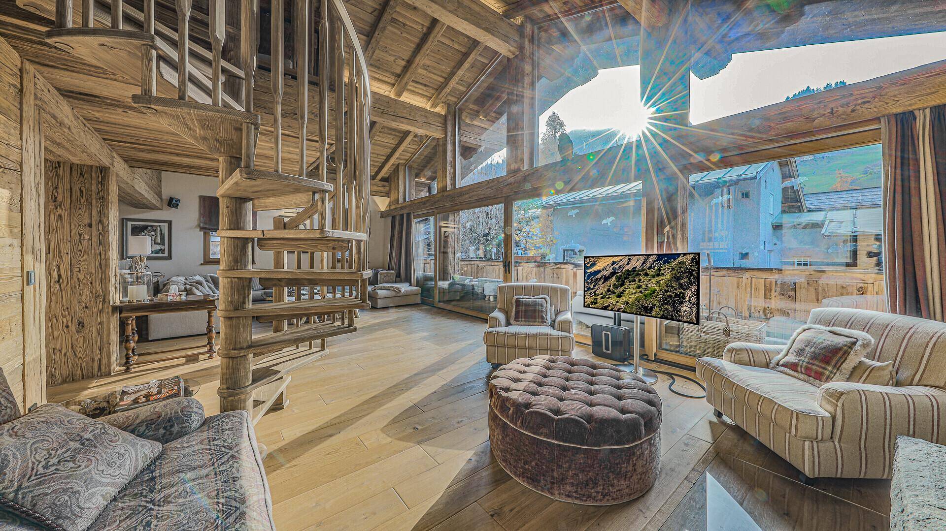 Helles Wohnzimmer im Chalet-Stil mit hohen Decken, großen Fenstern und Wendeltreppe.