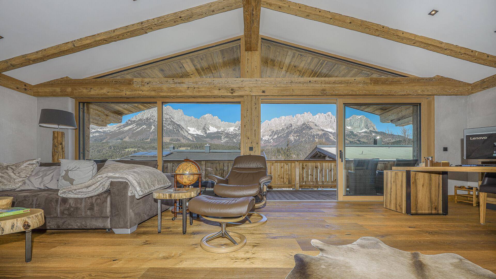 Heller Wohnbereich mit großen Fenstern, die einen weiten Blick auf die Berge bieten.