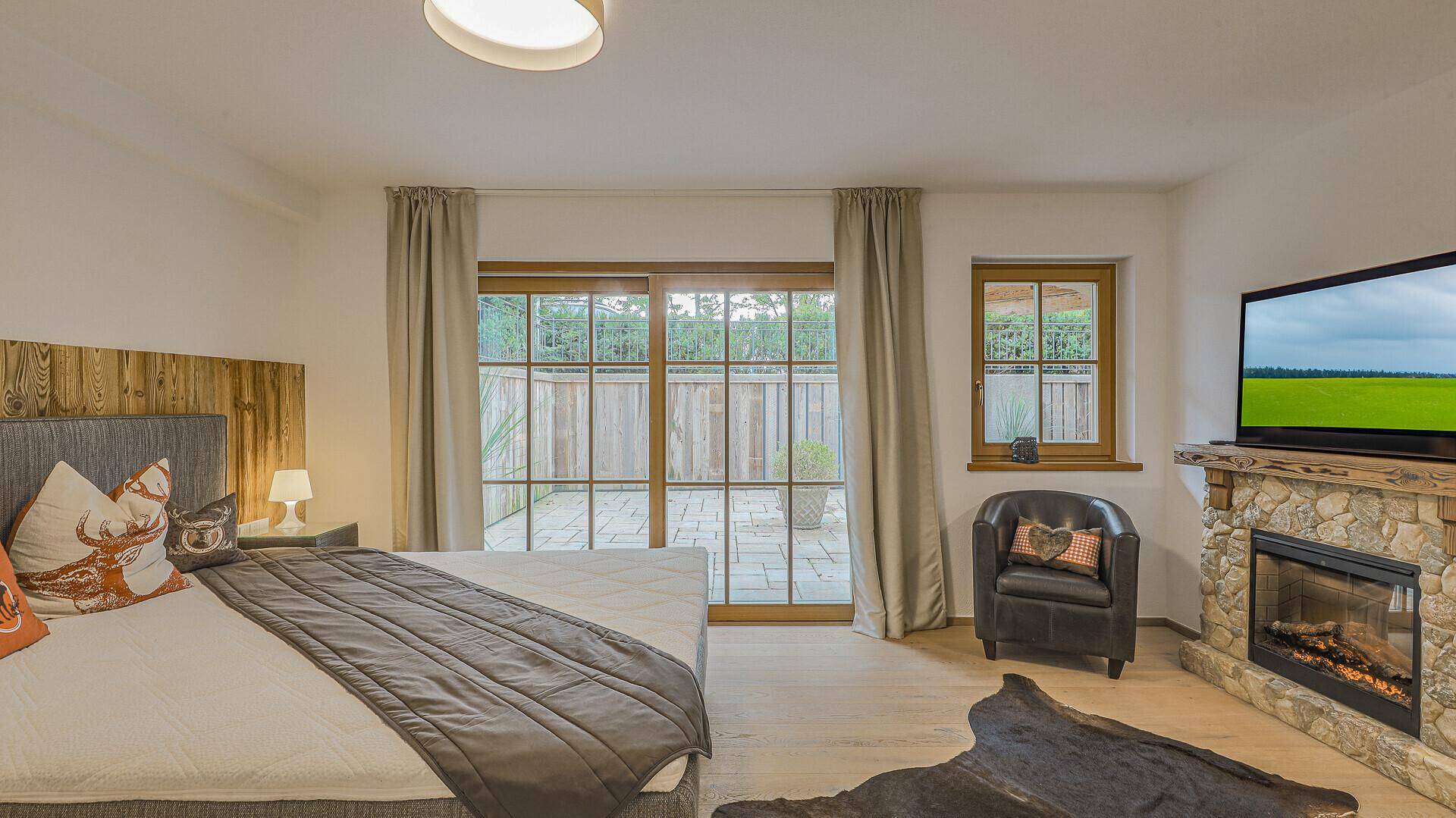 Gemütliches Schlafzimmer mit Kamin, Fernseher und direktem Zugang zu einer privaten Terrasse.
