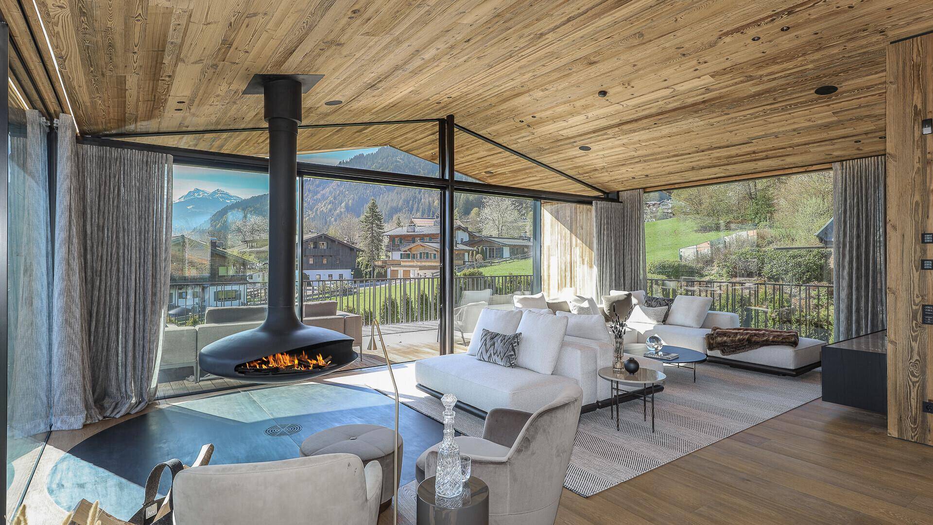 Geräumiger Wohnbereich mit Holzakzenten, modernem Kamin und weitem Blick auf die alpine Landschaft.