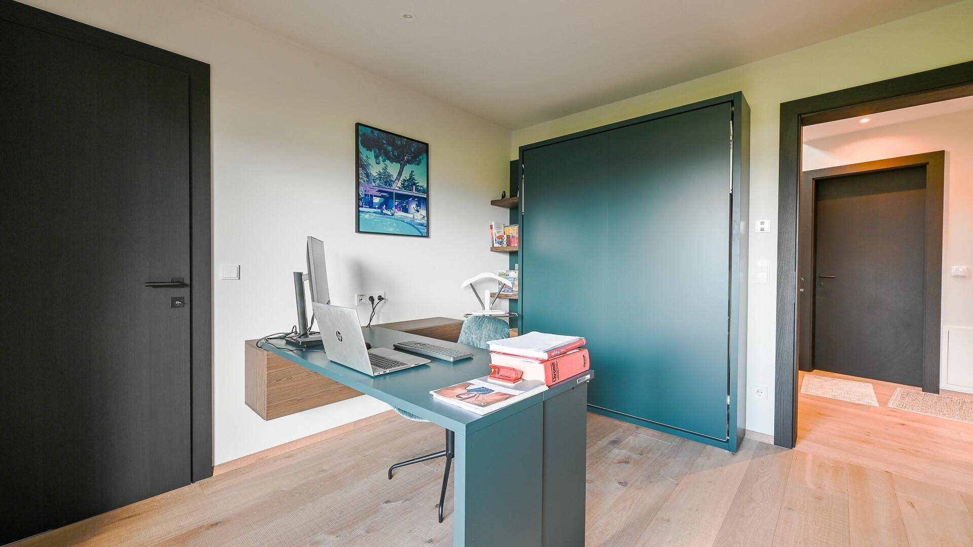 Modernes Arbeitszimmer mit Schreibtisch, Holzboden und dunklen Türen.