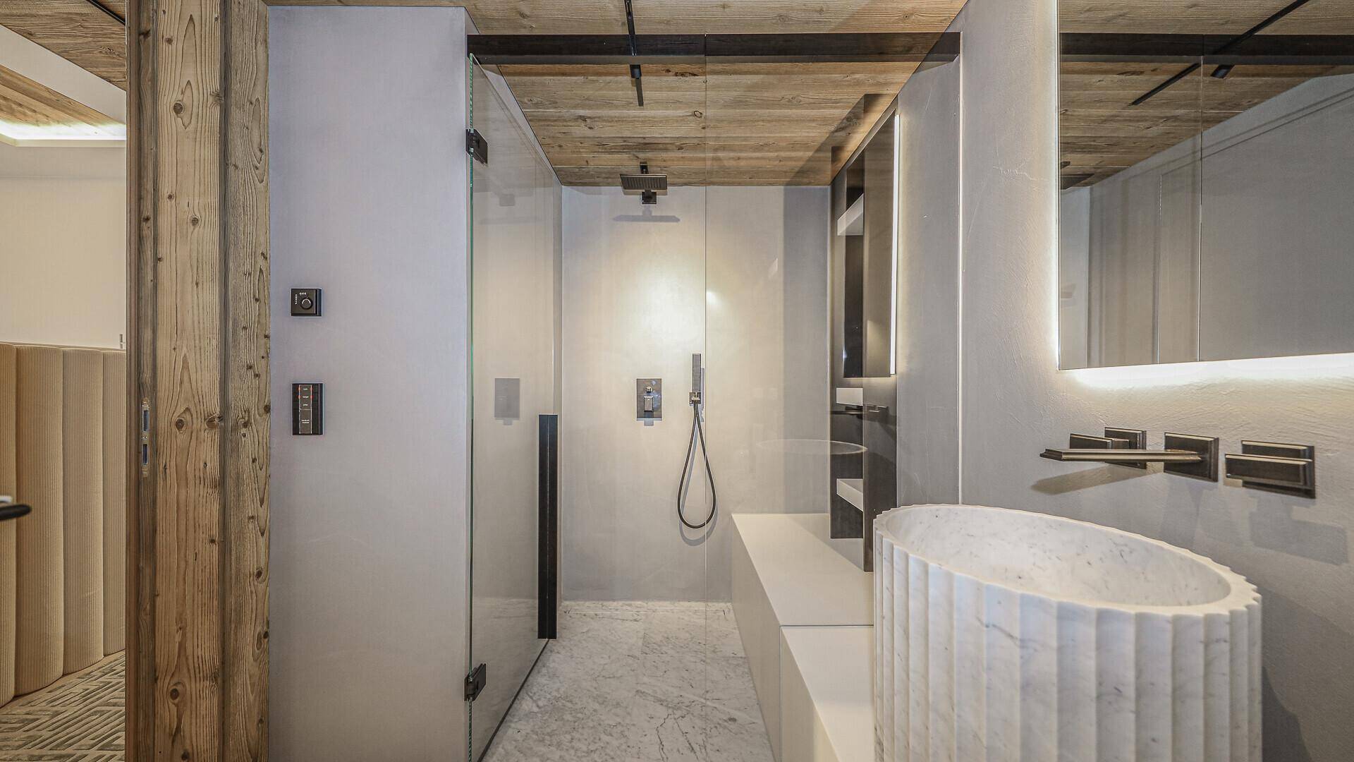 Modernes Badezimmer mit begehbarer Dusche, stilvollem Waschbecken und Holzakzenten.