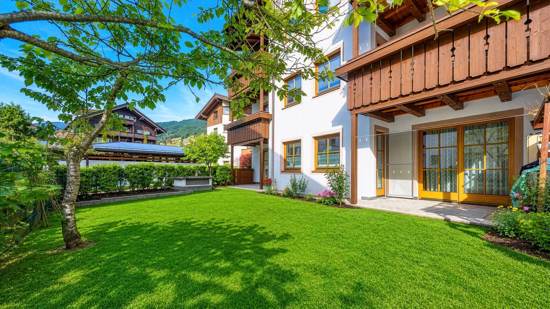 Gepflegter Gartenbereich mit Rasenfläche und Baumbestand vor der modernen Wohnanlage.