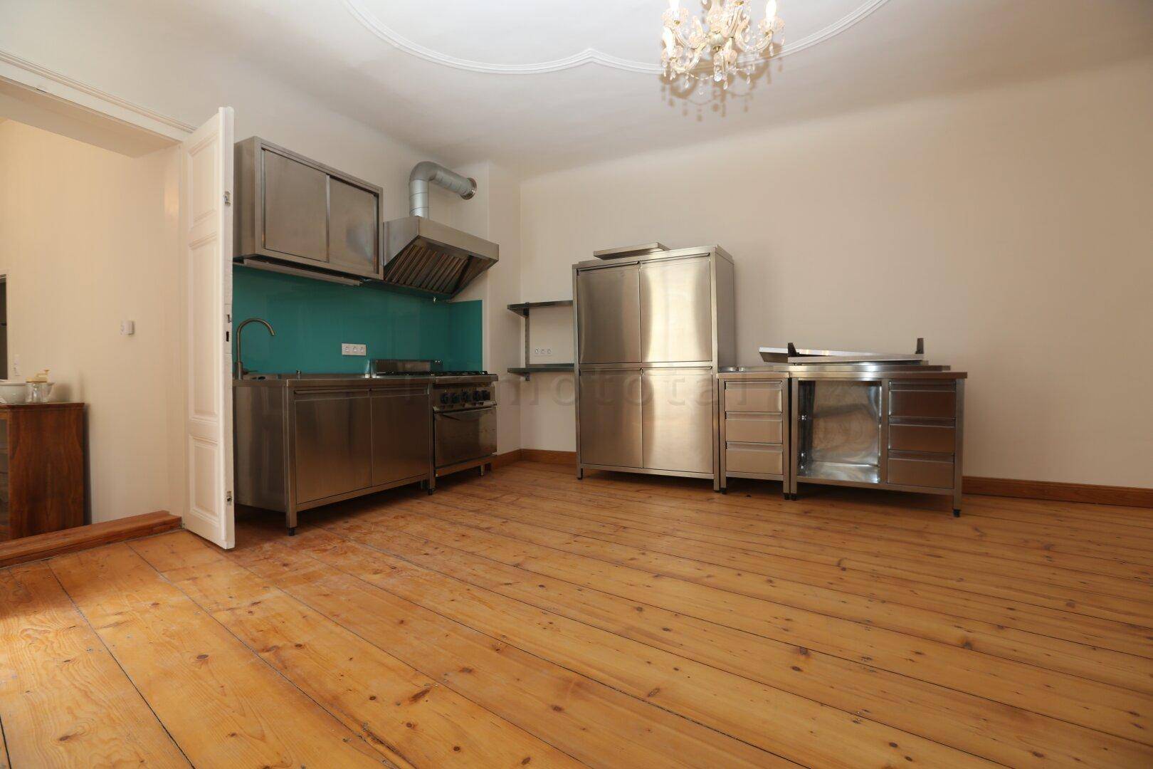 Geräumige Küche mit breiten Holzplanken, industrieller Edelstahlküche und einer Stuckdecke.