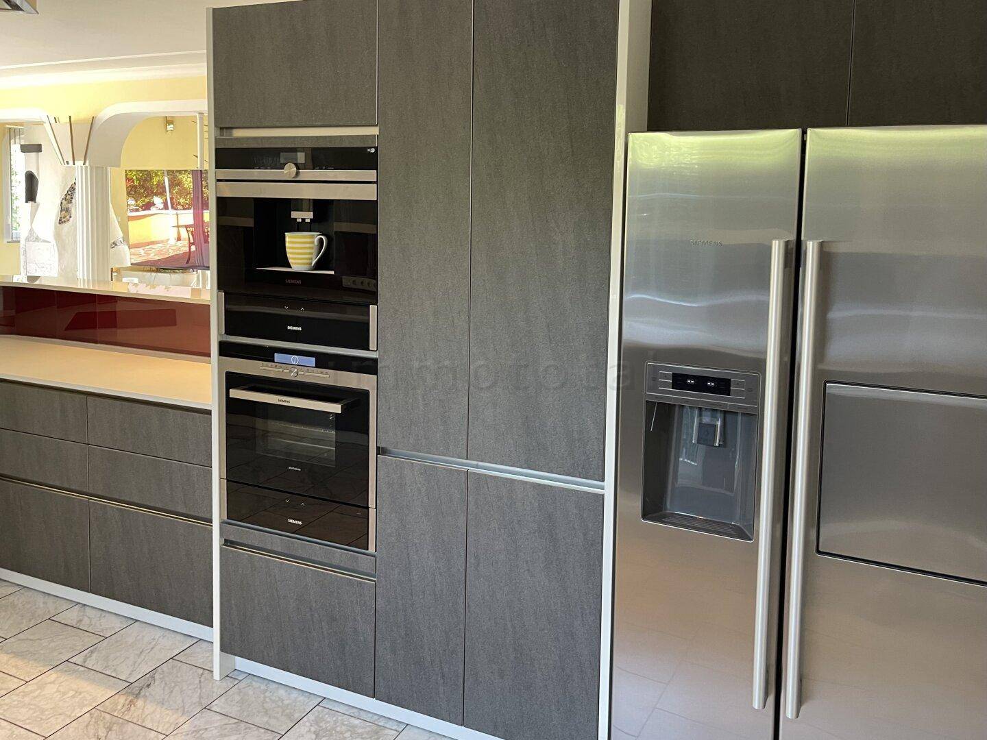 Hochwertige Einbauküche mit integriertem Backofen, Kaffeemaschine und großem Kühlschrank.