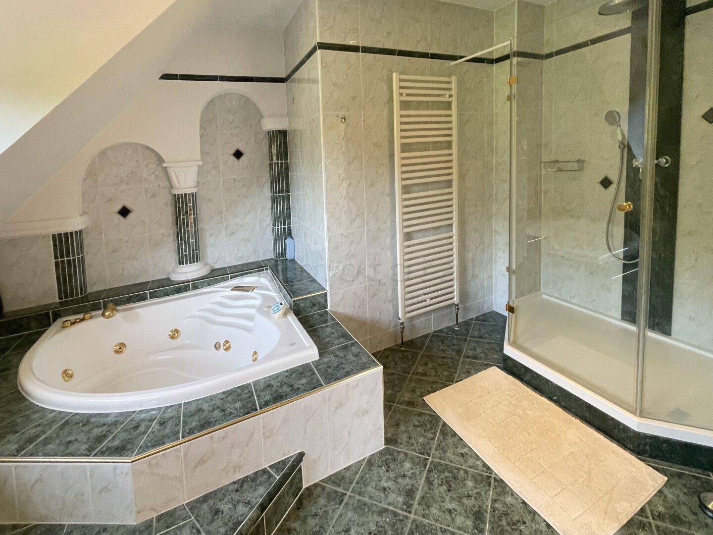 Geräumiges Badezimmer mit Whirlpool, separater Dusche und gefliesten Wänden und Böden.