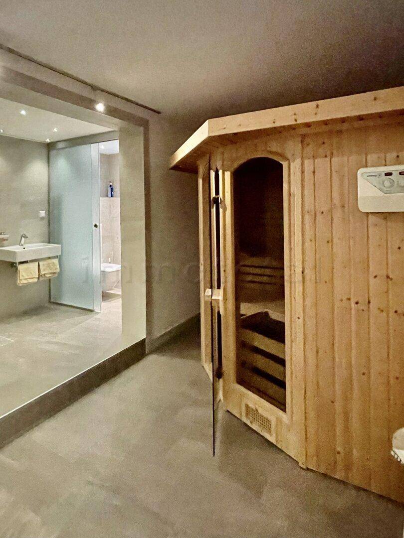 Modernes Badezimmer mit integrierter Holzsauna und minimalistischem Waschbeckenbereich.
