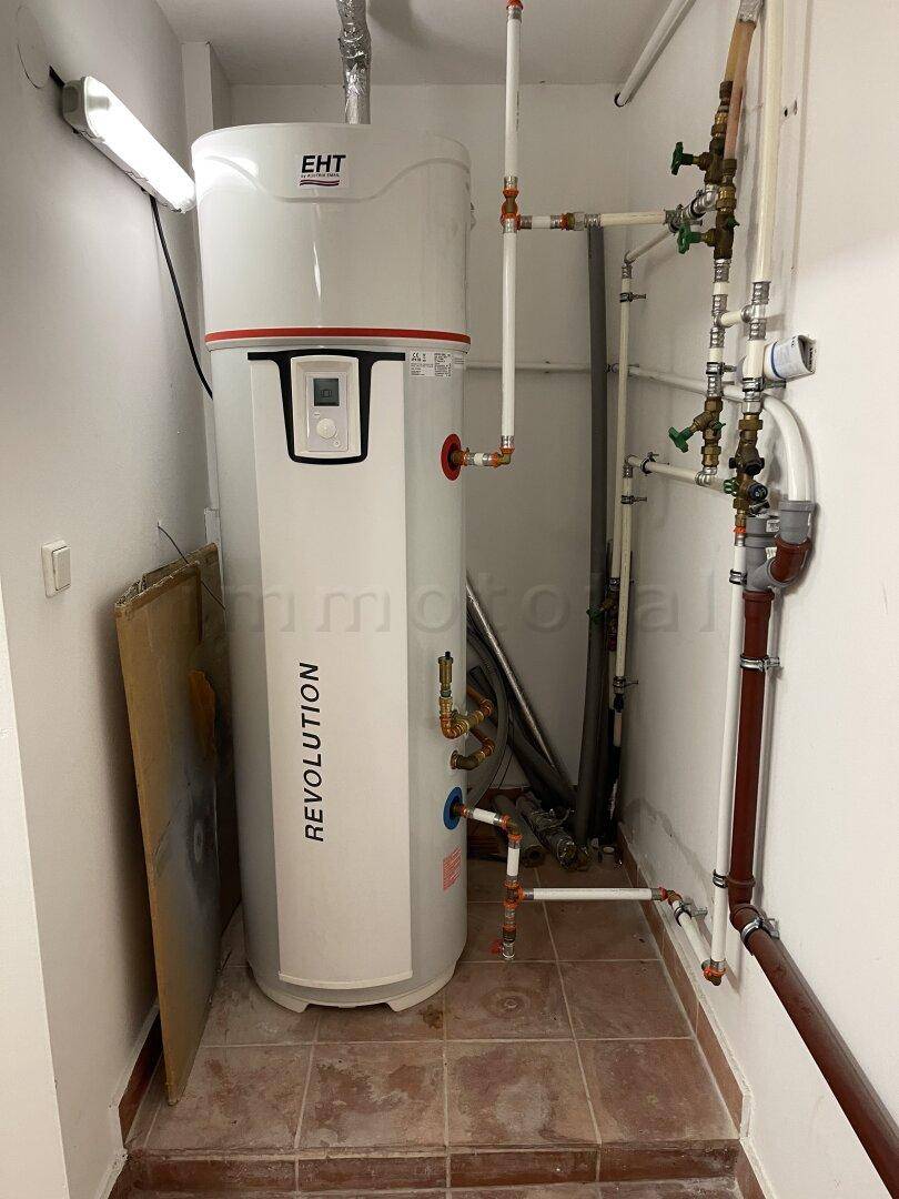 Technikraum mit großem Warmwasserspeicher und sichtbaren Rohrleitungen.