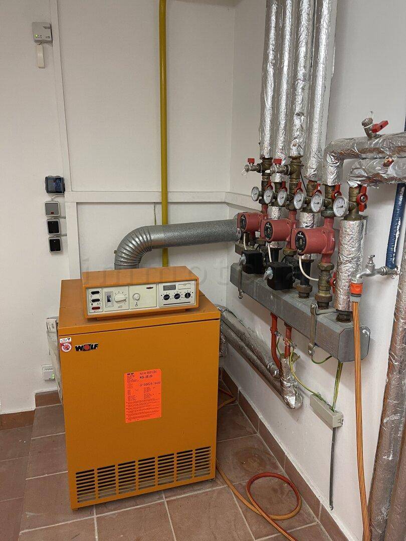 Heizungsraum mit einem Wolf-Heizkessel und komplexen Rohrinstallationen.