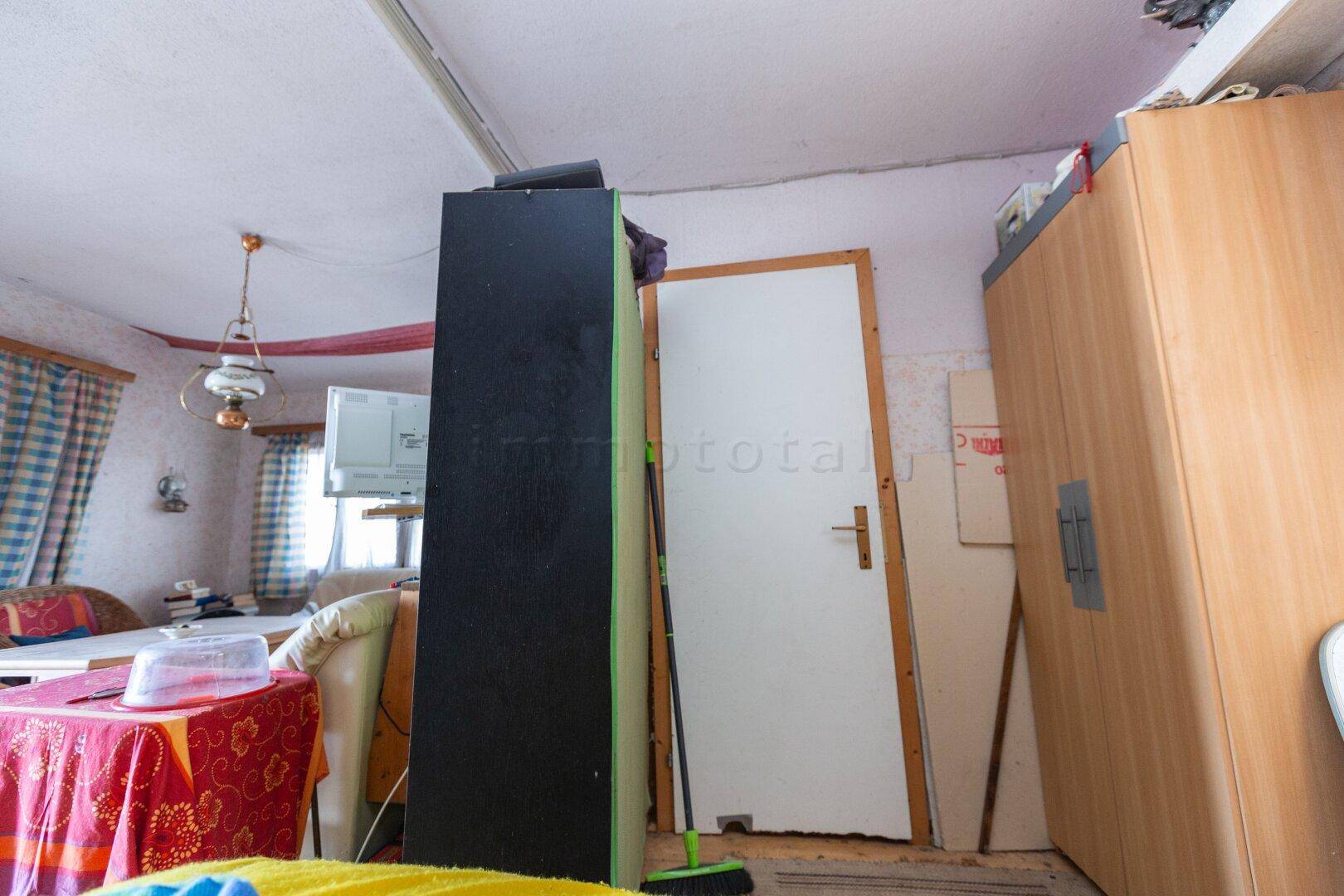 Innenraum mit Kleiderschrank und Tür, der verschiedene Wohnbereiche miteinander verbindet.