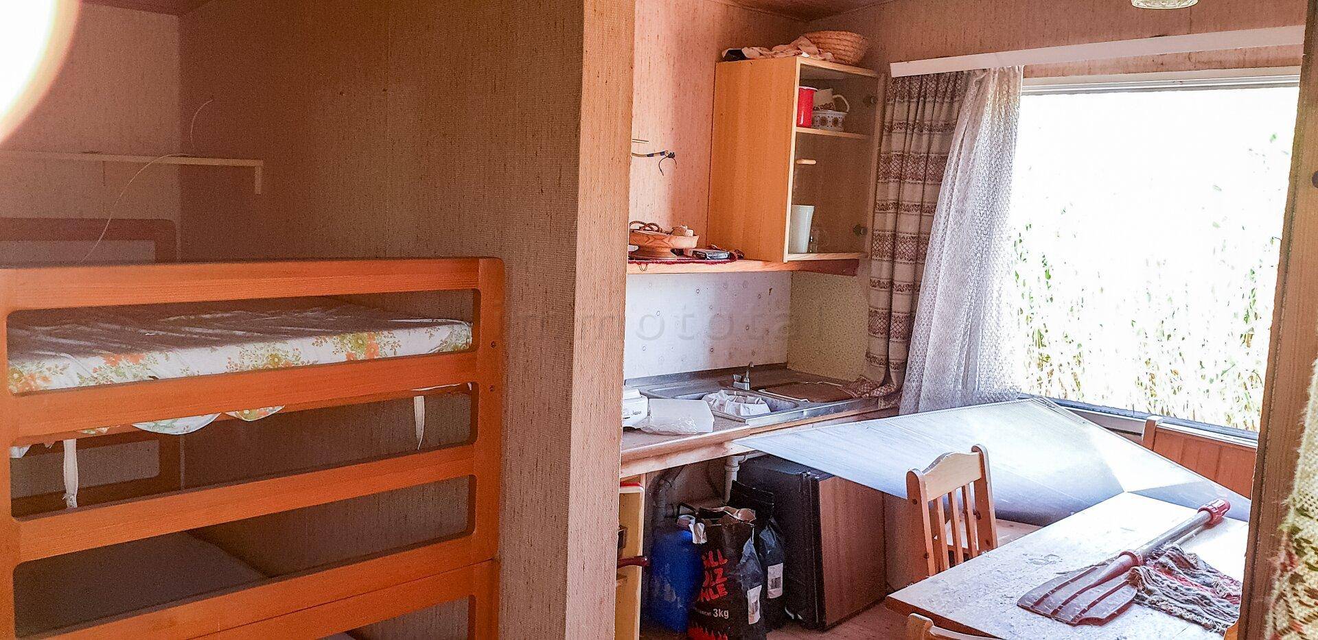 Kombinierter Wohn- und Schlafbereich mit Etagenbett und einfacher Küchenzeile am Fenster.