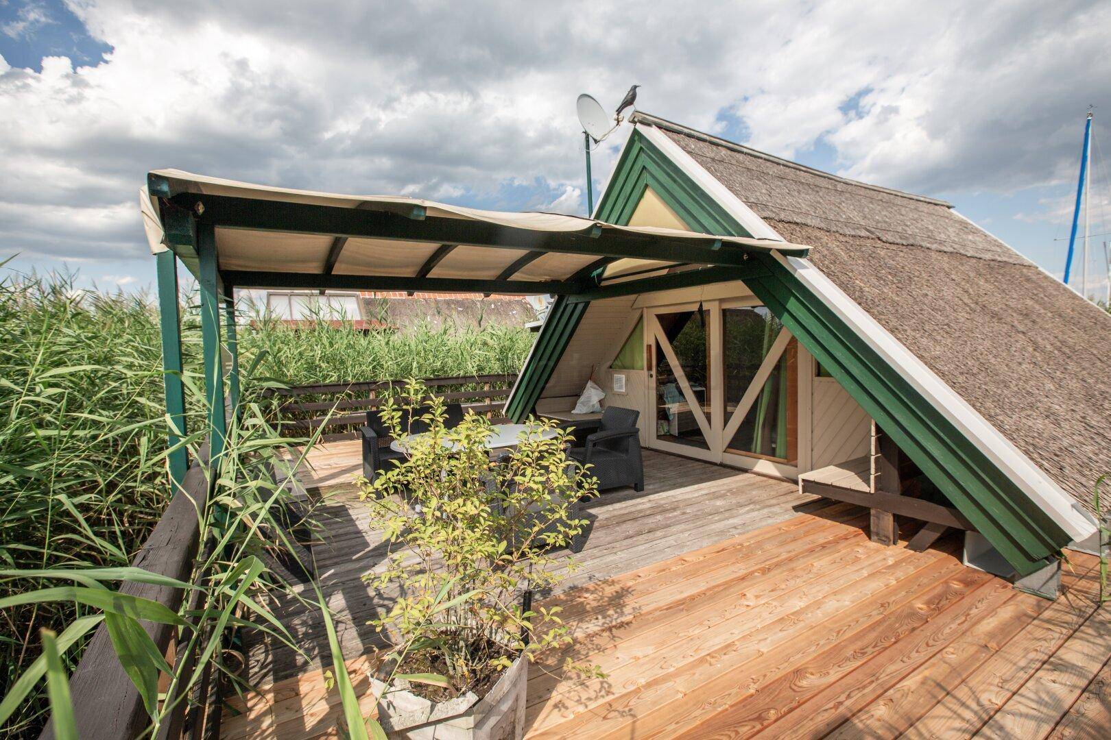 Gemütliche Holzterrasse mit Outdoor-Möbeln und Blick auf das umliegende Schilfgebiet.