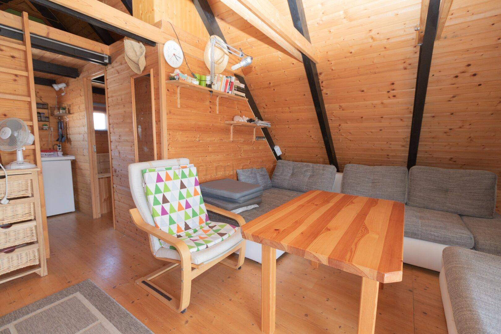Gemütlicher Wohnbereich mit Holzboden, bequemer Couch und einem kleinen Esstisch in rustikalem Ambiente.