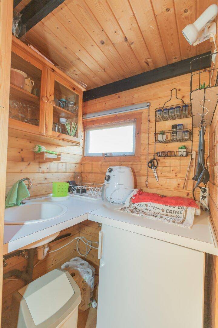Kompakte Küche mit Holzeinrichtung, Spülbecken und Stauraum, ideal für ein kleines Ferienhaus.