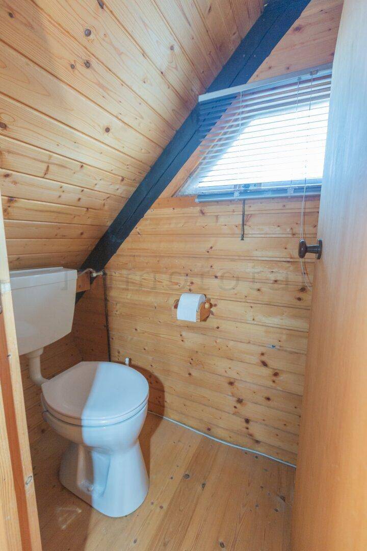 Separate Toilette mit Holzwänden und einem kleinen Fenster, einfach und funktional.