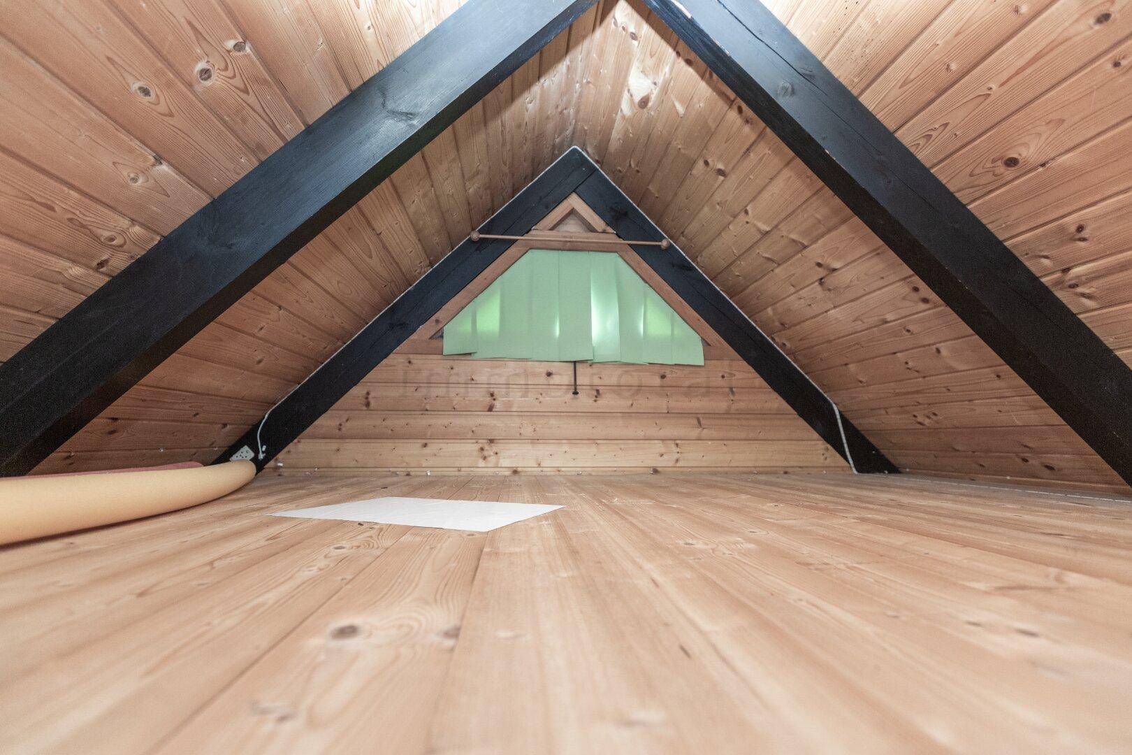 Leerer Dachboden mit Holzboden und sichtbaren Dachbalken, bietet zusätzlichen Stauraum.