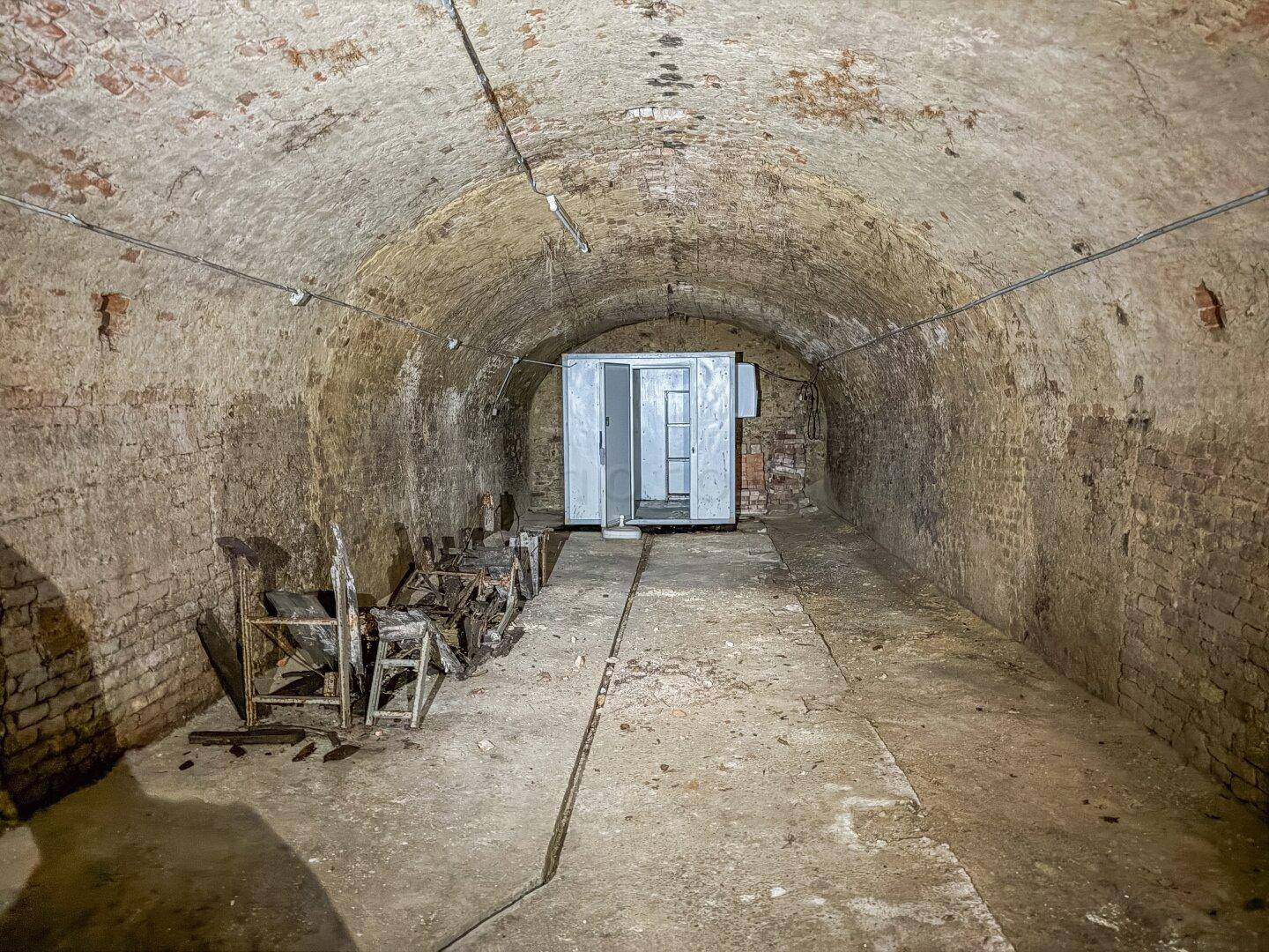 Langer, gewölbter Ziegelkeller mit historischem Charme und einfacher Beleuchtung.