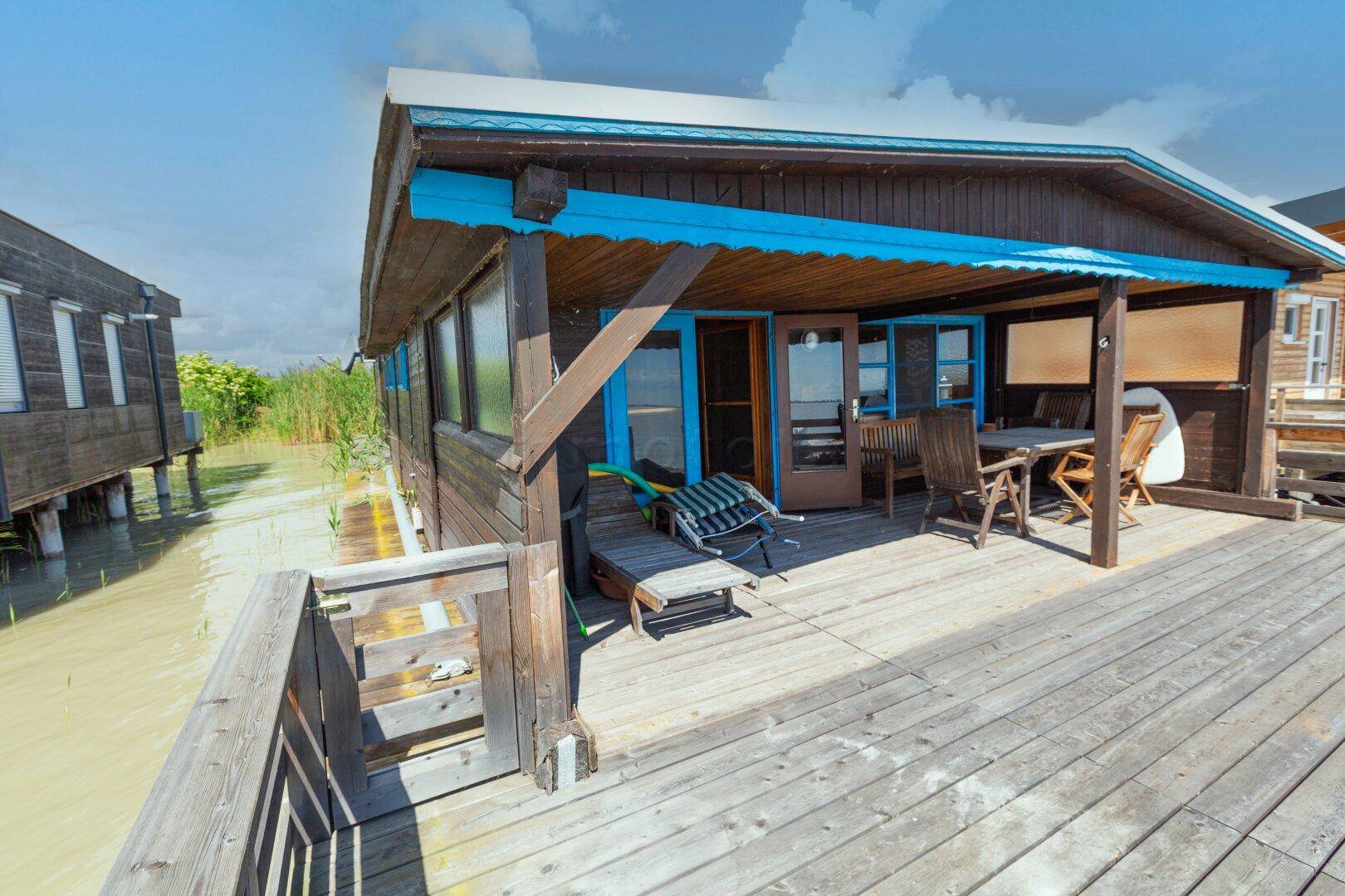 Holzhaus auf Stelzen mit weitläufiger Holzterrasse und Blick auf das Wasser.