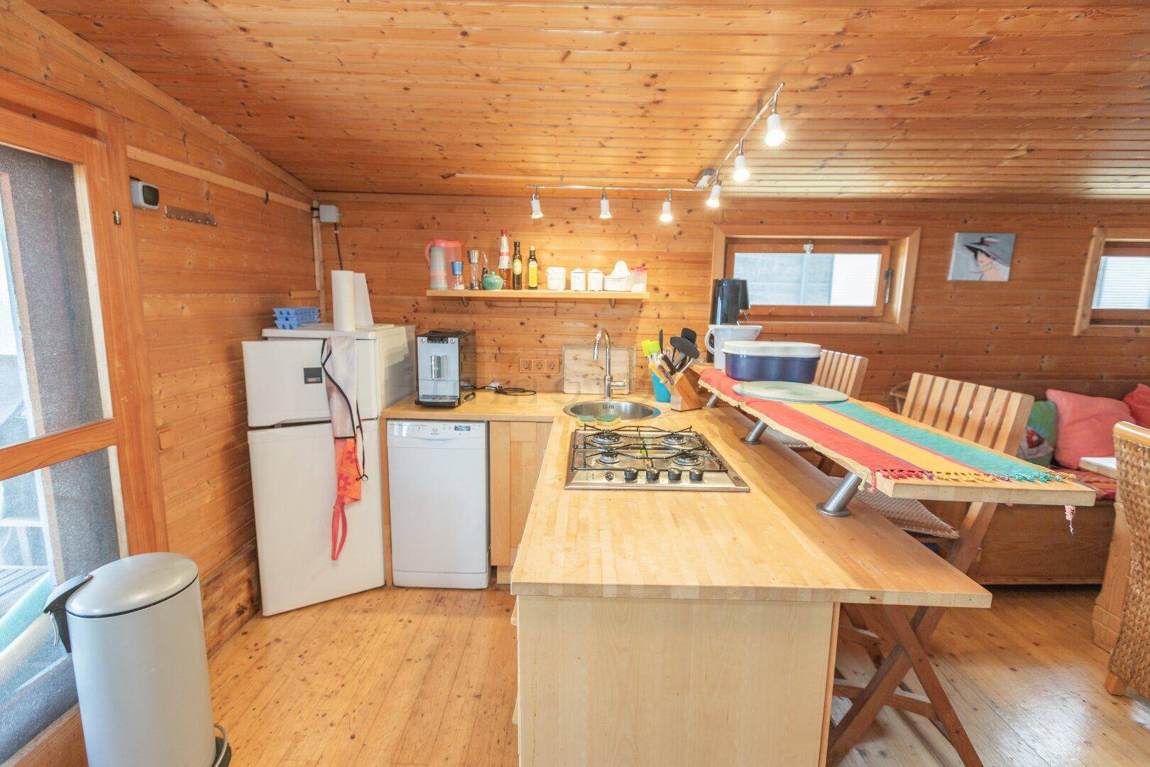 Kleine Küche mit Holztheke, Gasherd, Kühlschrank und Spülmaschine.