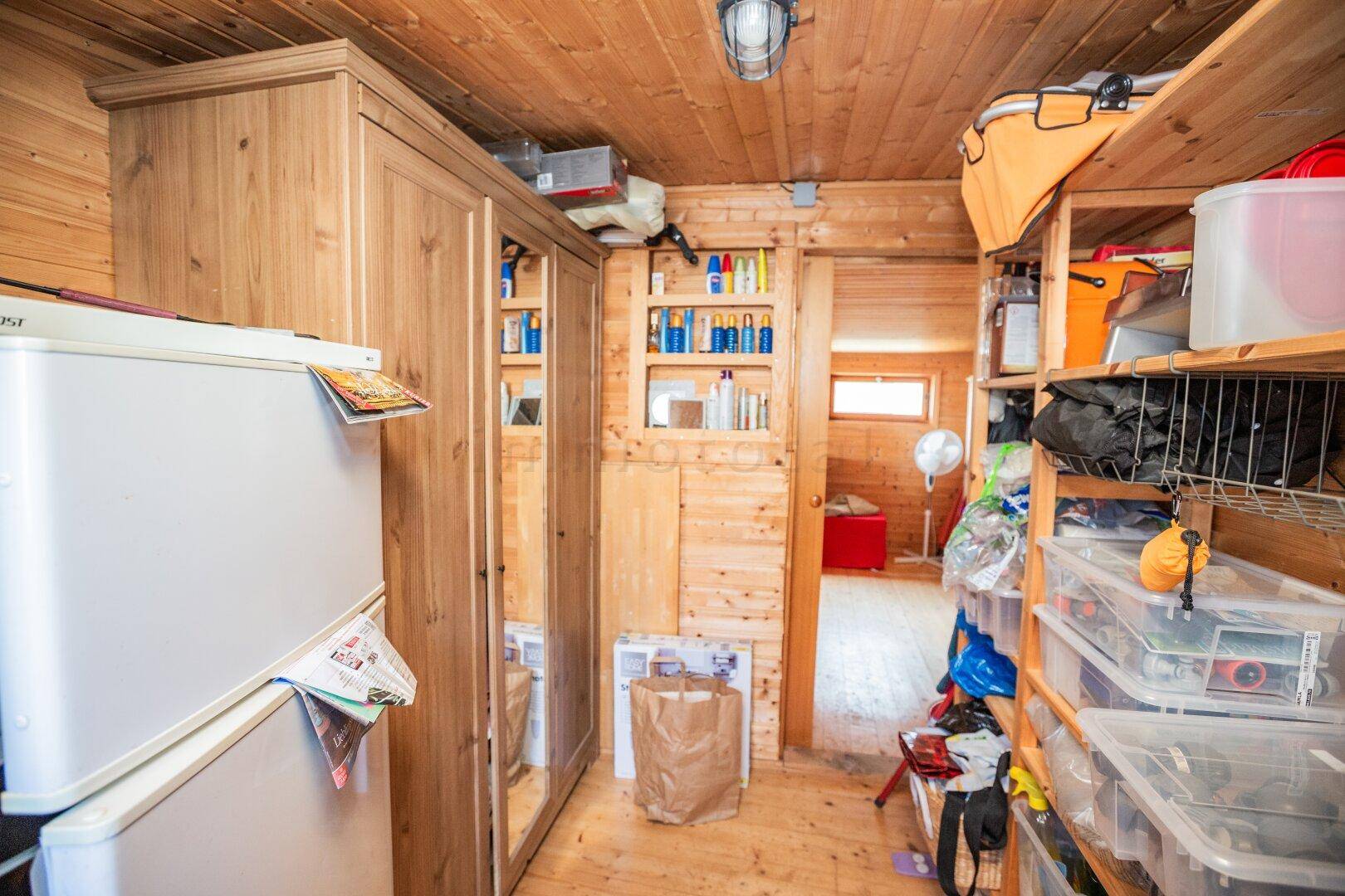 Geräumiger Abstellraum mit Holzschränken, Regalen und verschiedenen Utensilien.