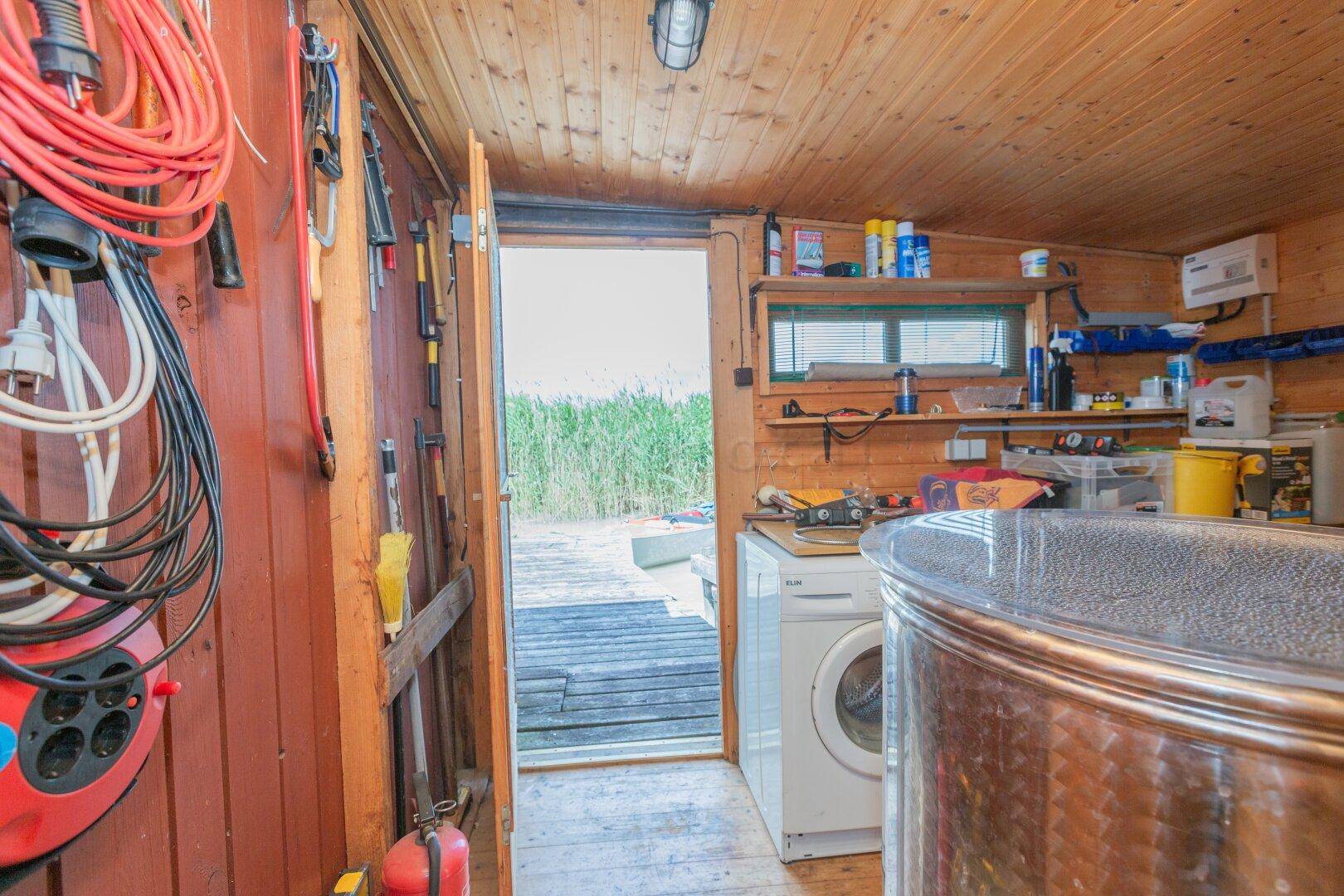 Hauswirtschaftsraum mit Waschmaschine und Zugang zur Terrasse mit Seeblick.