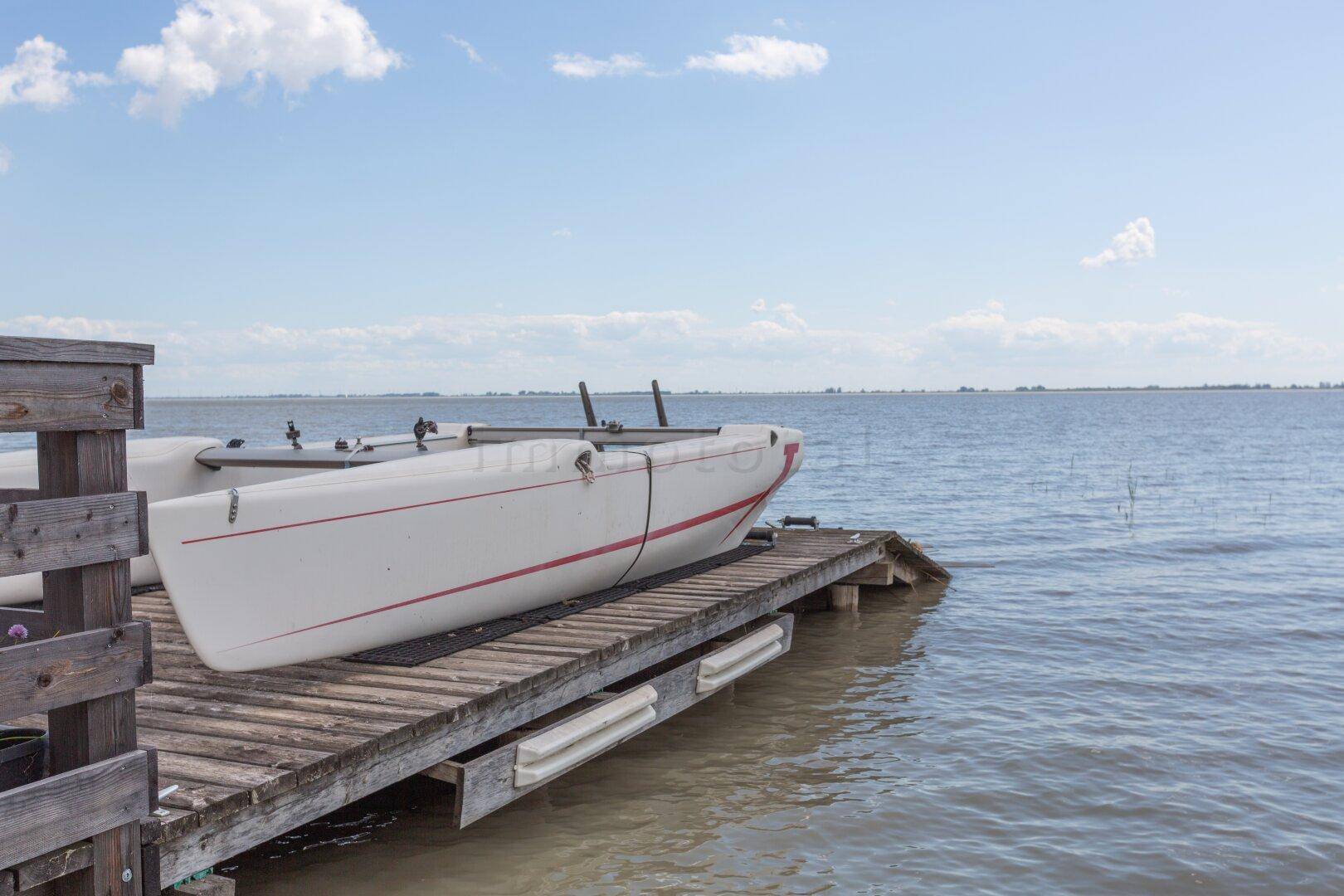 Ein kleines Boot liegt auf einem Holzsteg am Ufer eines Sees.