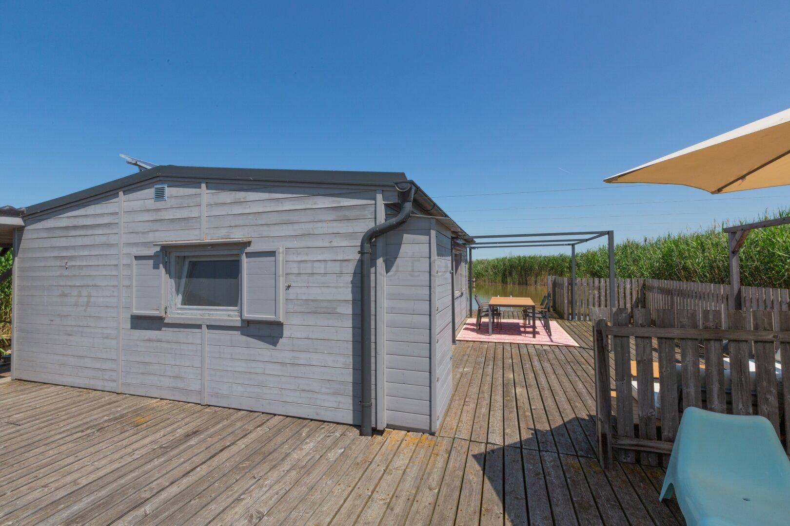 Seitenansicht des Hauses und der Holzterrasse mit Essbereich im Hintergrund.