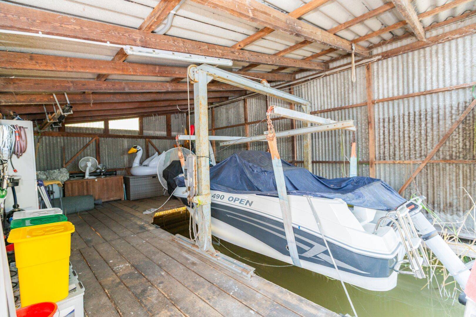 Innenansicht des Bootshauses mit einem Boot auf einem Lift und Holzkonstruktion.