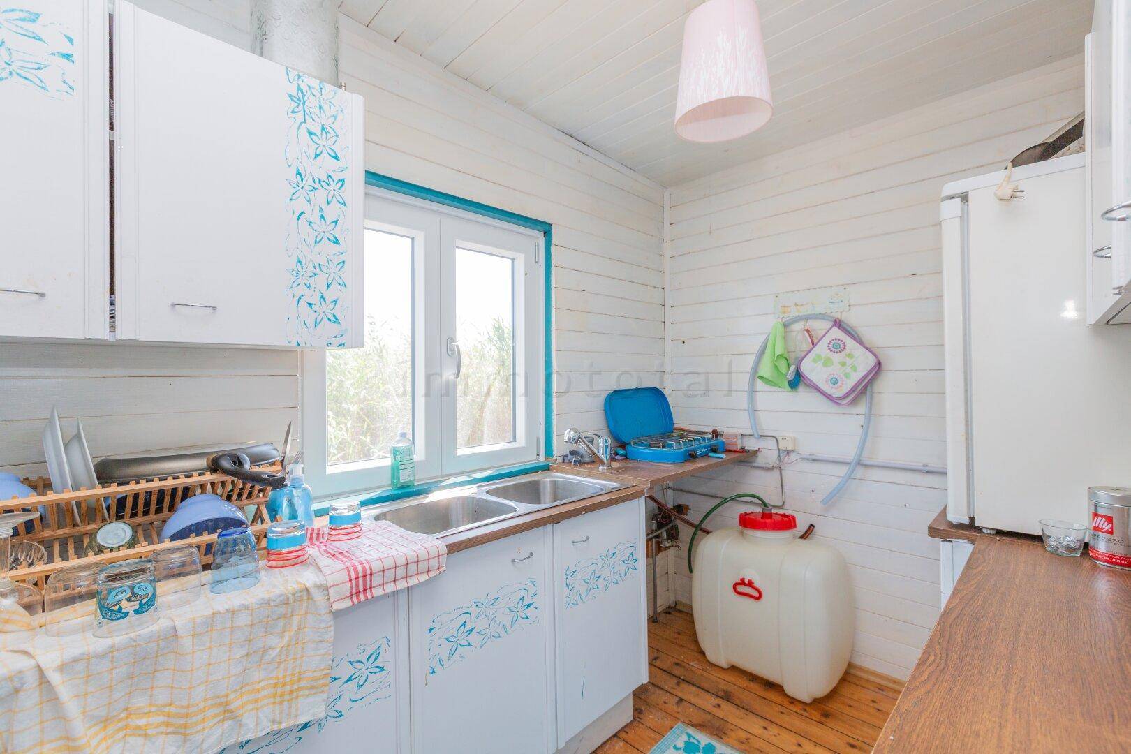 Kleine Küche mit Doppelspüle, Holztheke und weiß-blauen Schränken in rustikalem Stil.