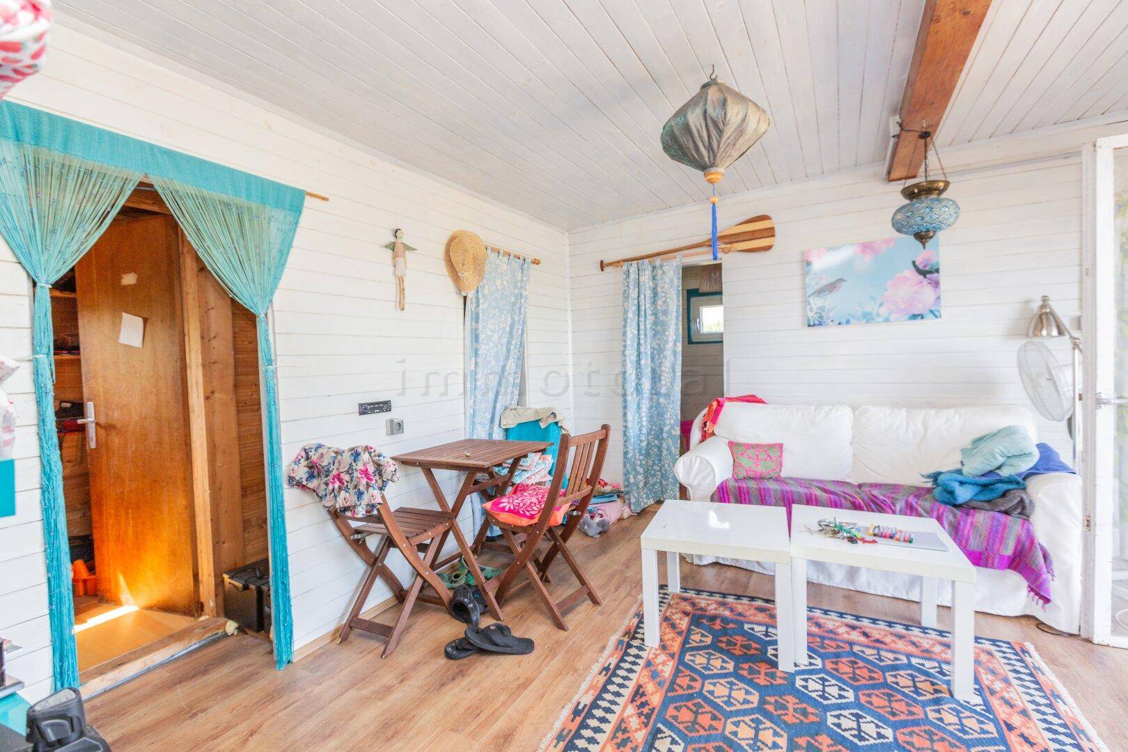 Wohnbereich mit Sofa, Esstisch und Zugang zur Terrasse, dekoriert mit orientalischem Teppich.