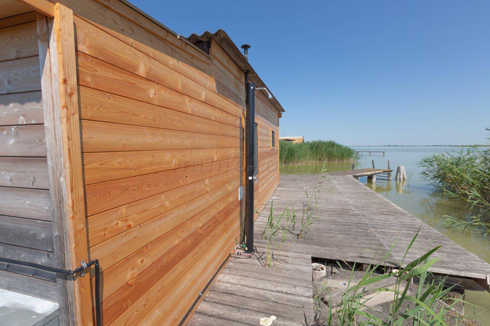 Holzterrasse am Wasser mit Blick auf den See und die weite Schilflandschaft.