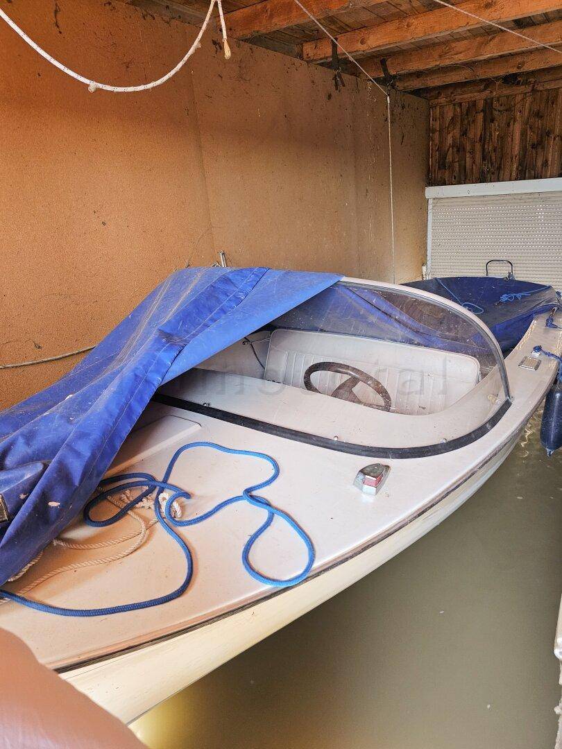 Ein Boot liegt in einem rustikalen Bootshaus mit sichtbaren Holzbalken und direktem Wasserzugang.