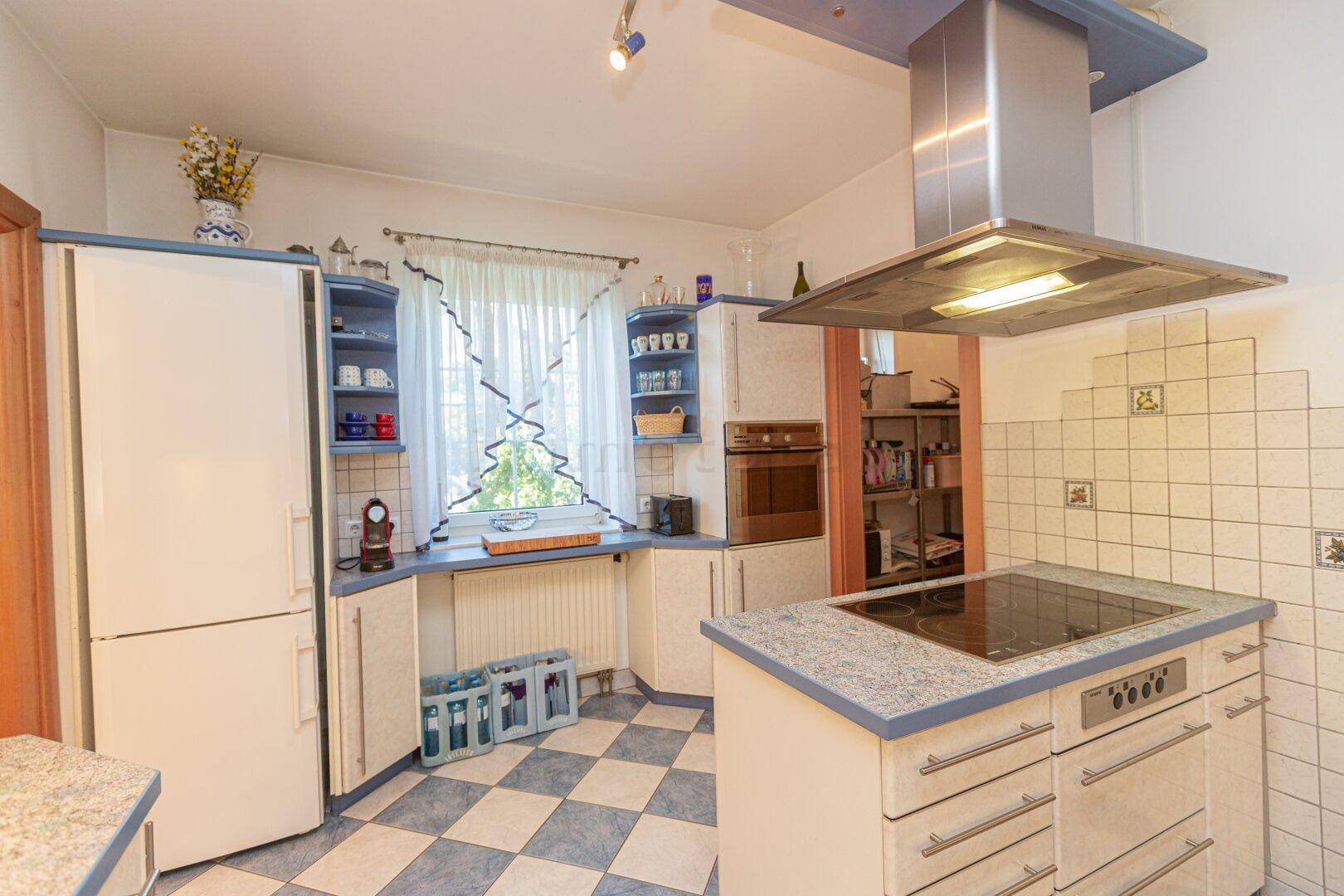 Traditionelle Küche mit blauen und weißen Schränken, kariertem Boden und Kochinsel.
