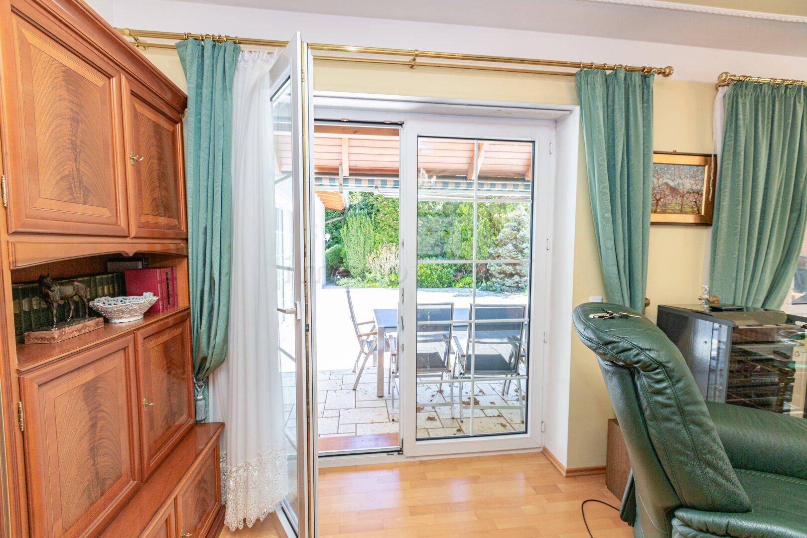 Wohnzimmer mit Zugang zur Terrasse und Blick auf den grünen Gartenbereich.