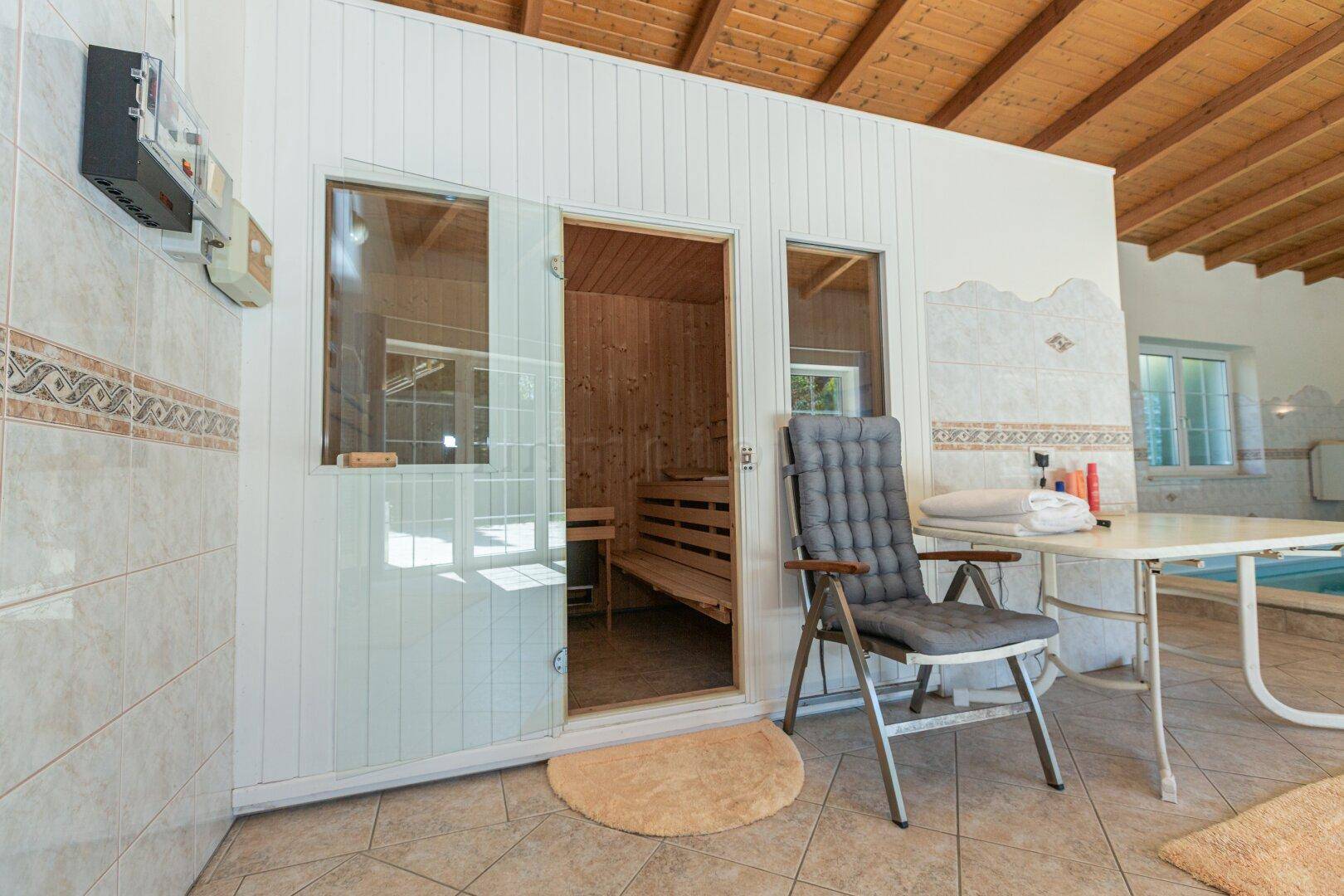 Wellnessbereich mit Sauna, Fliesenboden und Zugang zum Poolbereich.
