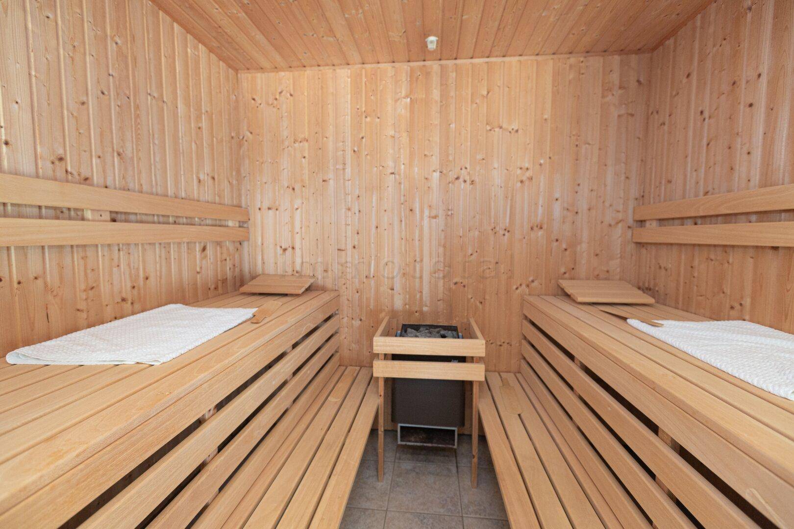 Holzvertäfelte Sauna mit Bänken und Heizofen für entspannende Momente.