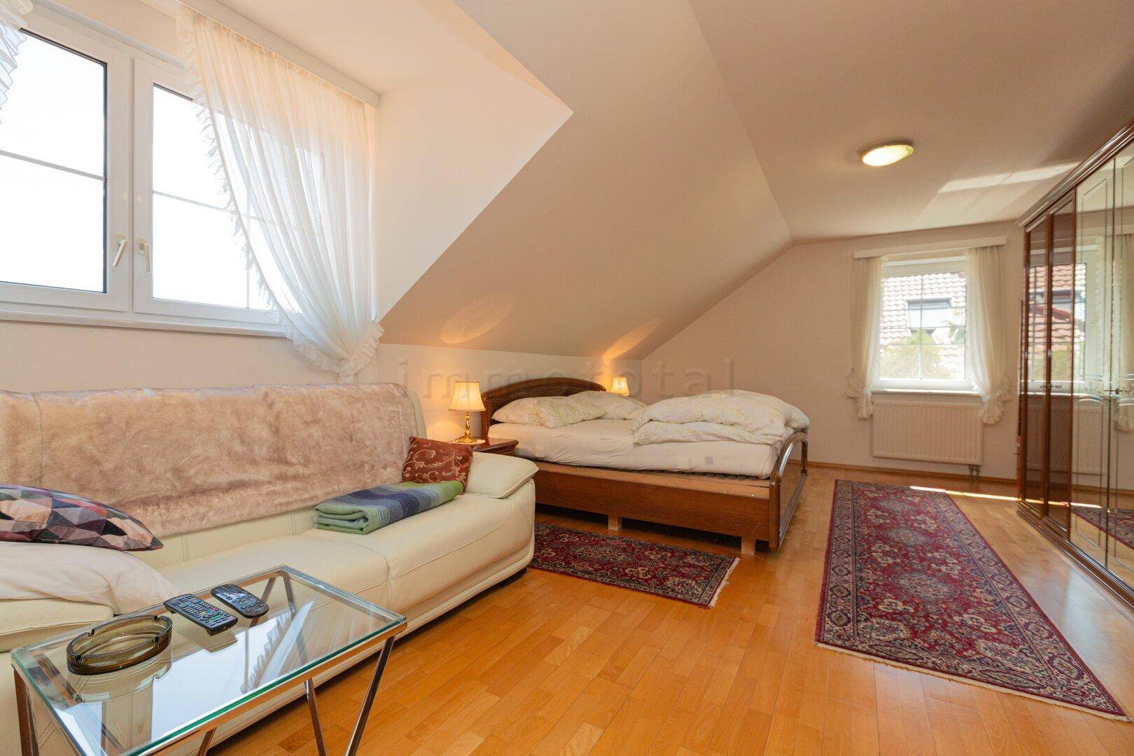 Gemütliches Schlafzimmer im Dachgeschoss mit Holzboden und Dachschrägen.