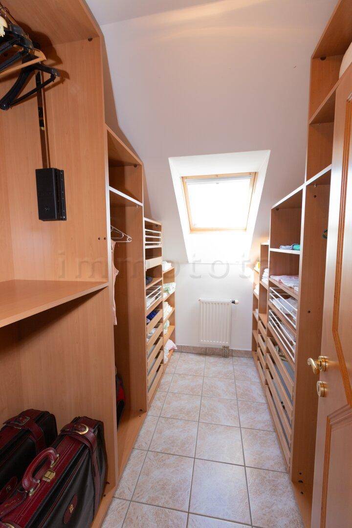 Begehbarer Kleiderschrank mit Regalen, Hängestangen und Dachfenster.