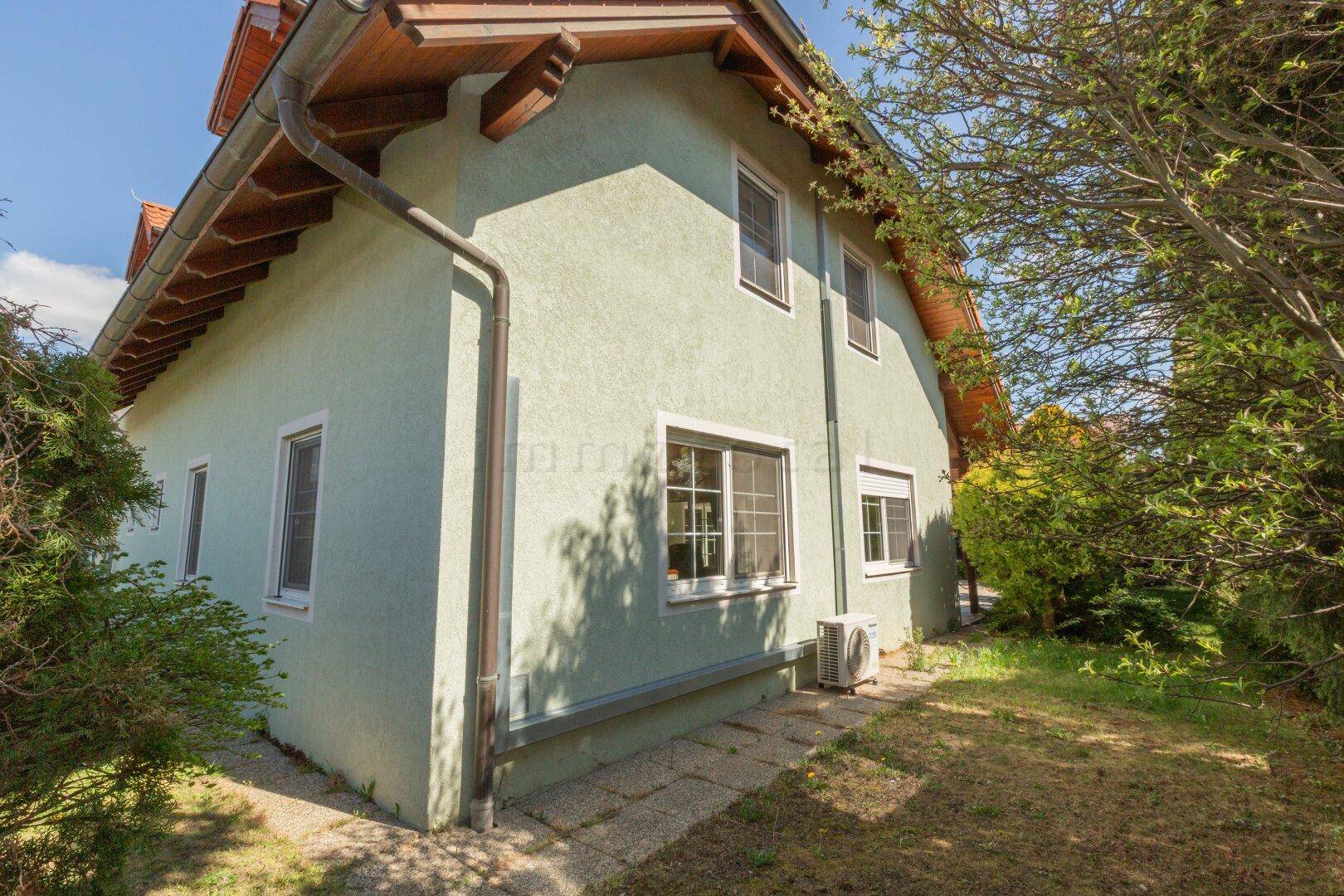 Seitenansicht des Hauses mit grüner Fassade und Gartenbereich.