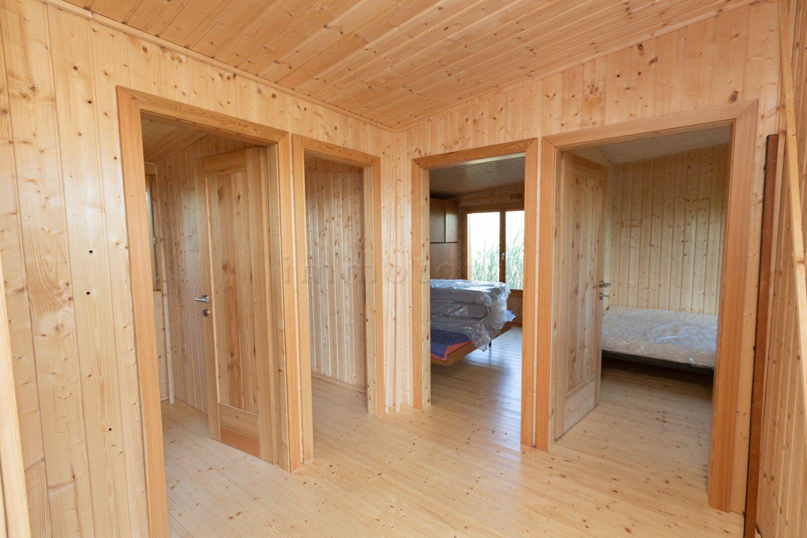 Heller Flur mit Holzvertäfelung und mehreren Holztüren, die zu den angrenzenden Räumen führen.