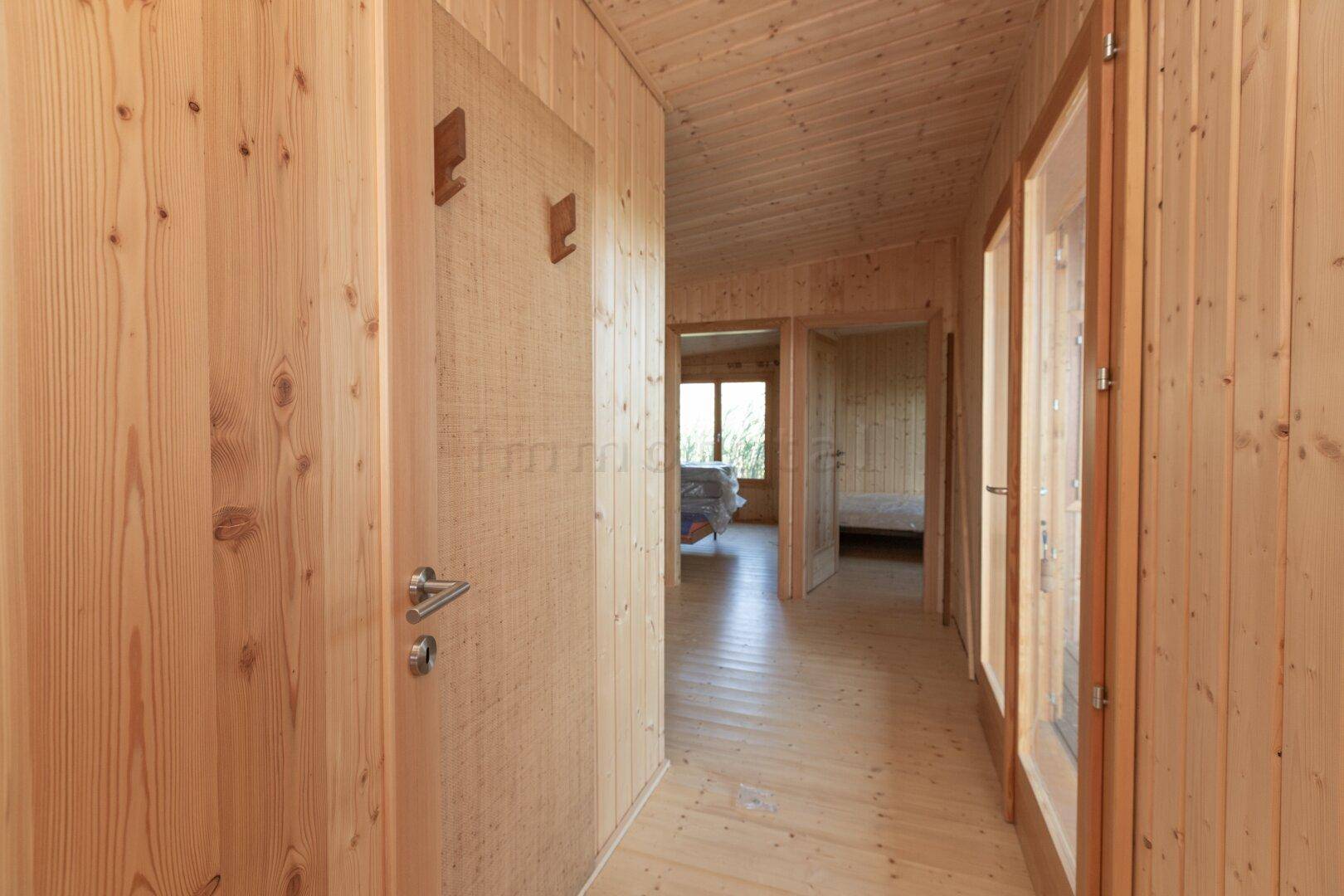 Langer Flur mit Holzvertäfelung, Holzboden und Türen, die zu den Schlafzimmern führen.