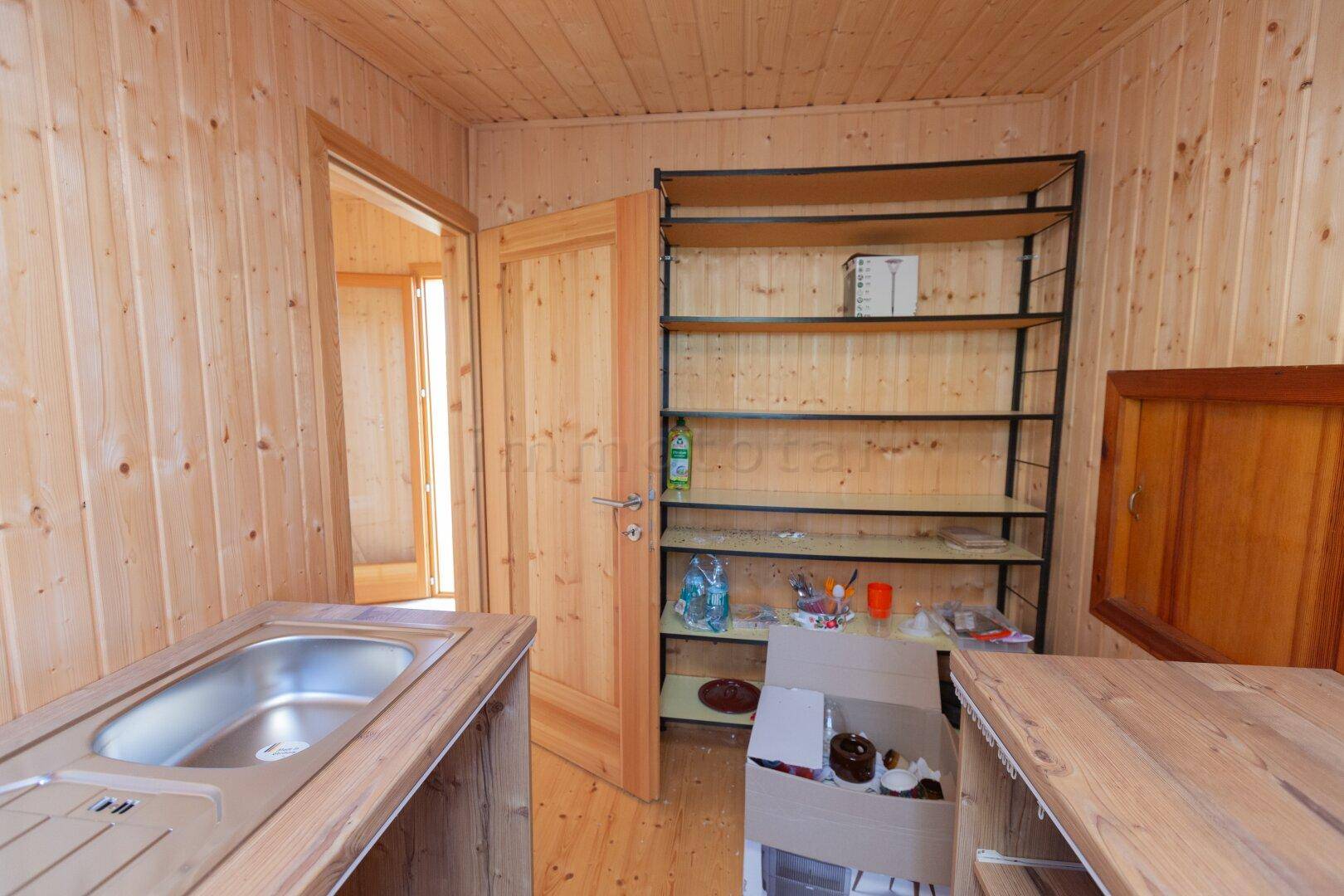 Funktionale Küche mit Holz-Arbeitsplatten, Spülbecken und einem Metallregal für Stauraum.