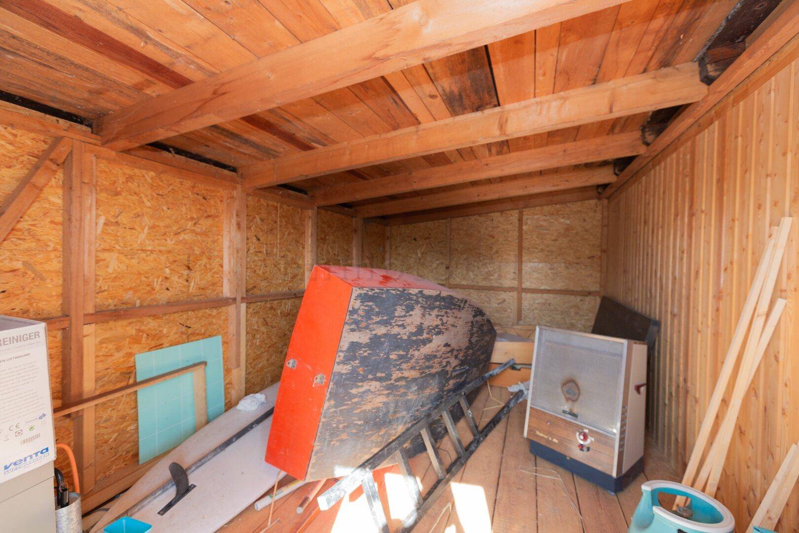 Geräumiger Abstellraum mit Holzkonstruktion, einem Boot und verschiedenen Lagergegenständen.