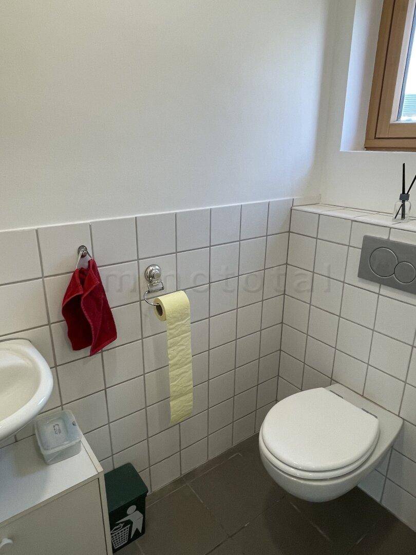 Separate Toilette mit Fenster und Wand-WC.