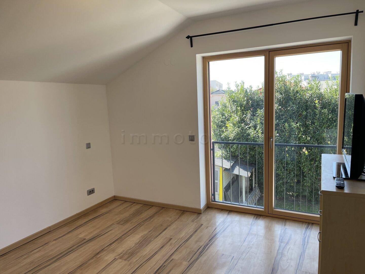 Geräumiges Schlafzimmer mit Holzboden und französischem Balkon mit Blick ins Grüne.